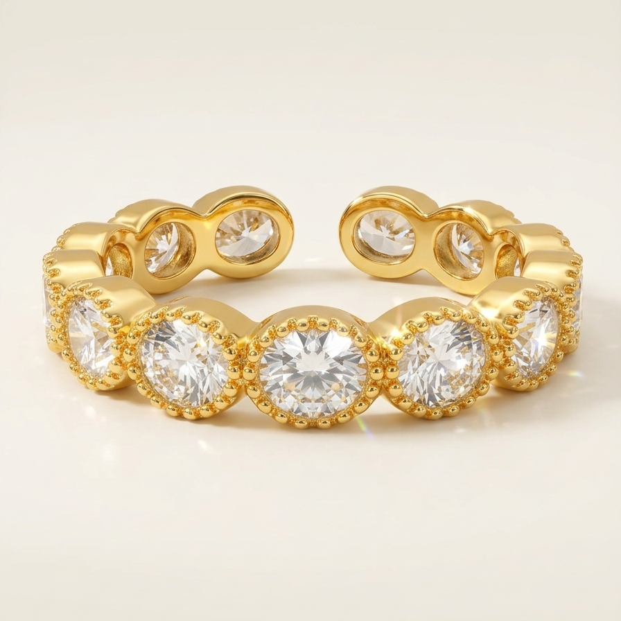 Close up of an 18k gold plated eternity band ring featuring a row of sparkling CZ diamonds with vintage beaded edges, resting on a textured white ceramic surface.