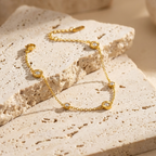 Gold chain bracelet with Roman numeral and crystal station charms on jewelry box.