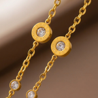 Gold chain bracelet with Roman numeral and crystal station charms on jewelry box.