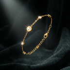 Gold chain bracelet with Roman numeral and crystal station charms on jewelry box.