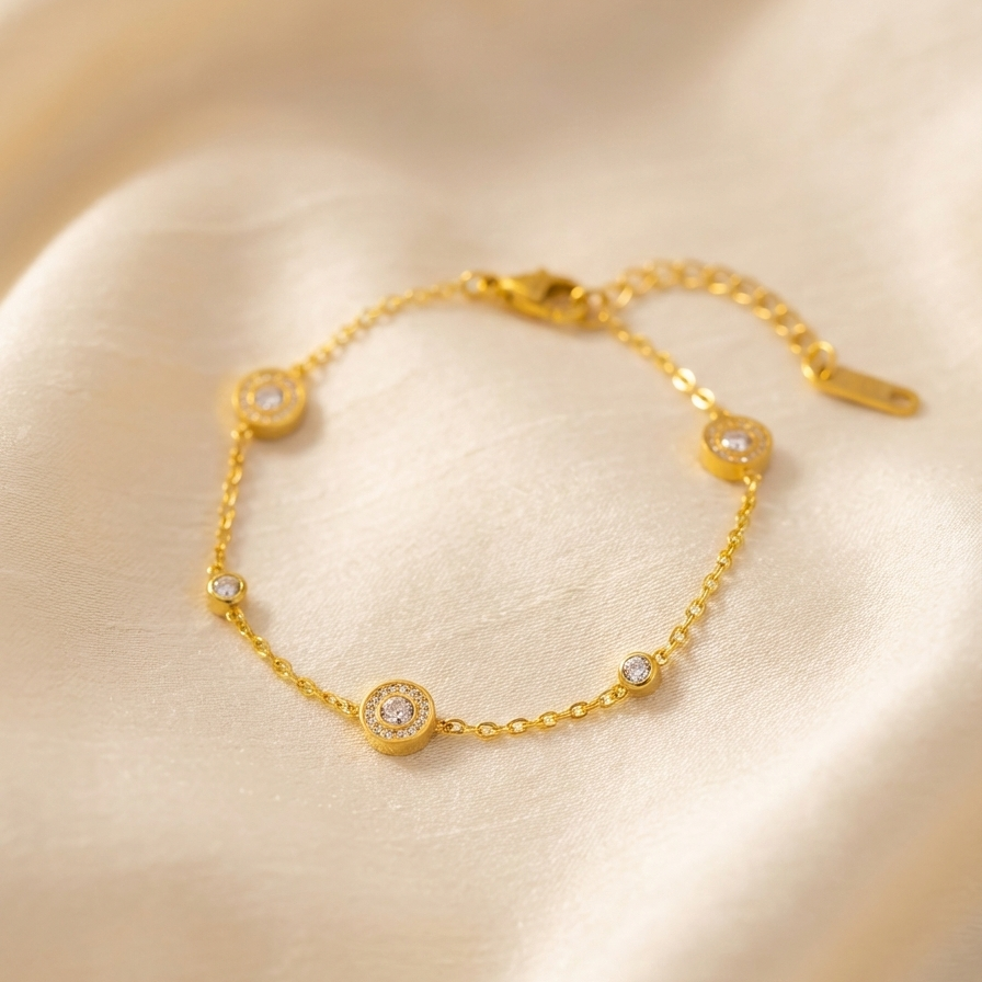 Gold chain bracelet with Roman numeral and crystal station charms on jewelry box.