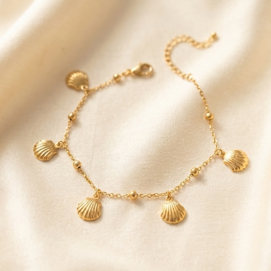 Gold chain bracelet with five dangling scallop shell charms on white packaging.