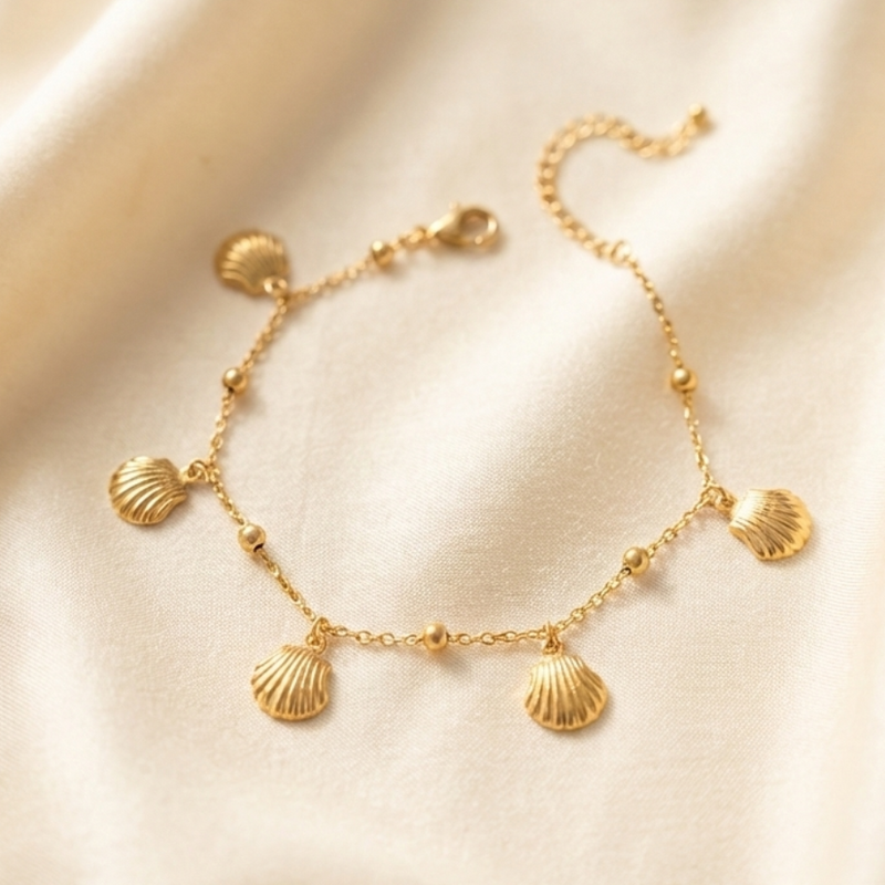 Gold chain bracelet with five dangling scallop shell charms on white packaging.