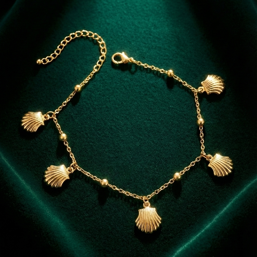 Gold chain bracelet with five dangling scallop shell charms on white packaging.