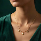 Gold shell charm necklace with three scallop shells on beaded chain white background.