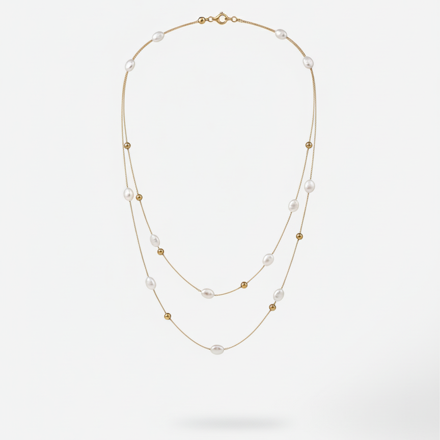 Double strand gold necklace with white baroque pearls and gold beads on white surface.