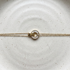 Gold chain bracelet with interlocking circles, mother of pearl inlay and engraved LOVE text on stone background.