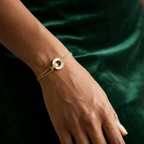 Gold chain bracelet with interlocking circles, mother of pearl inlay and engraved LOVE text on stone background.