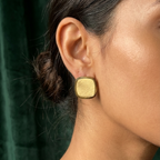 Square gold stud earrings with matte brushed texture and polished rim on white surface.