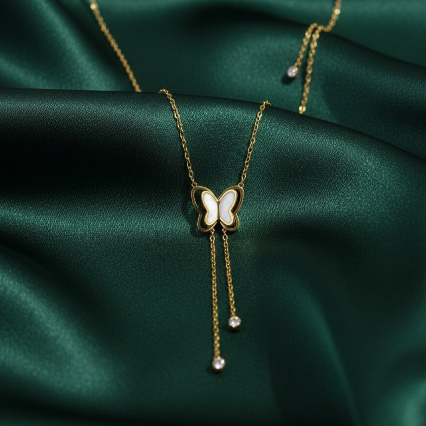 Gold butterfly necklace with dangling tassels and white inlay on packaging card.