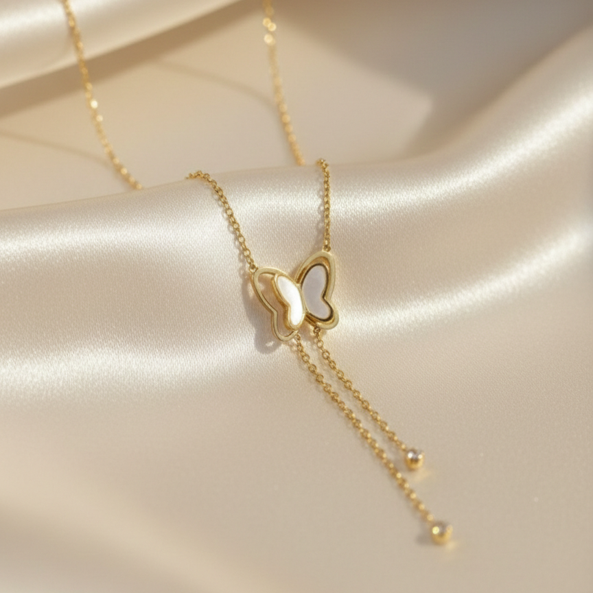Gold butterfly necklace with dangling tassels and white inlay on packaging card.