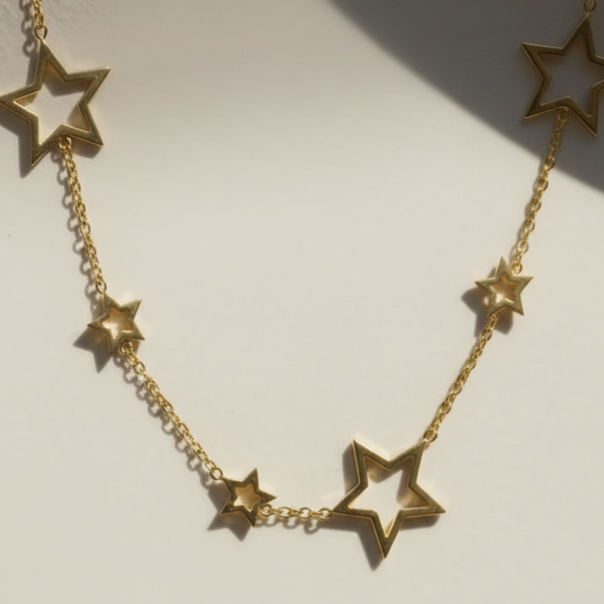 Gold chain necklace with multiple open star charms spaced out on white plate.