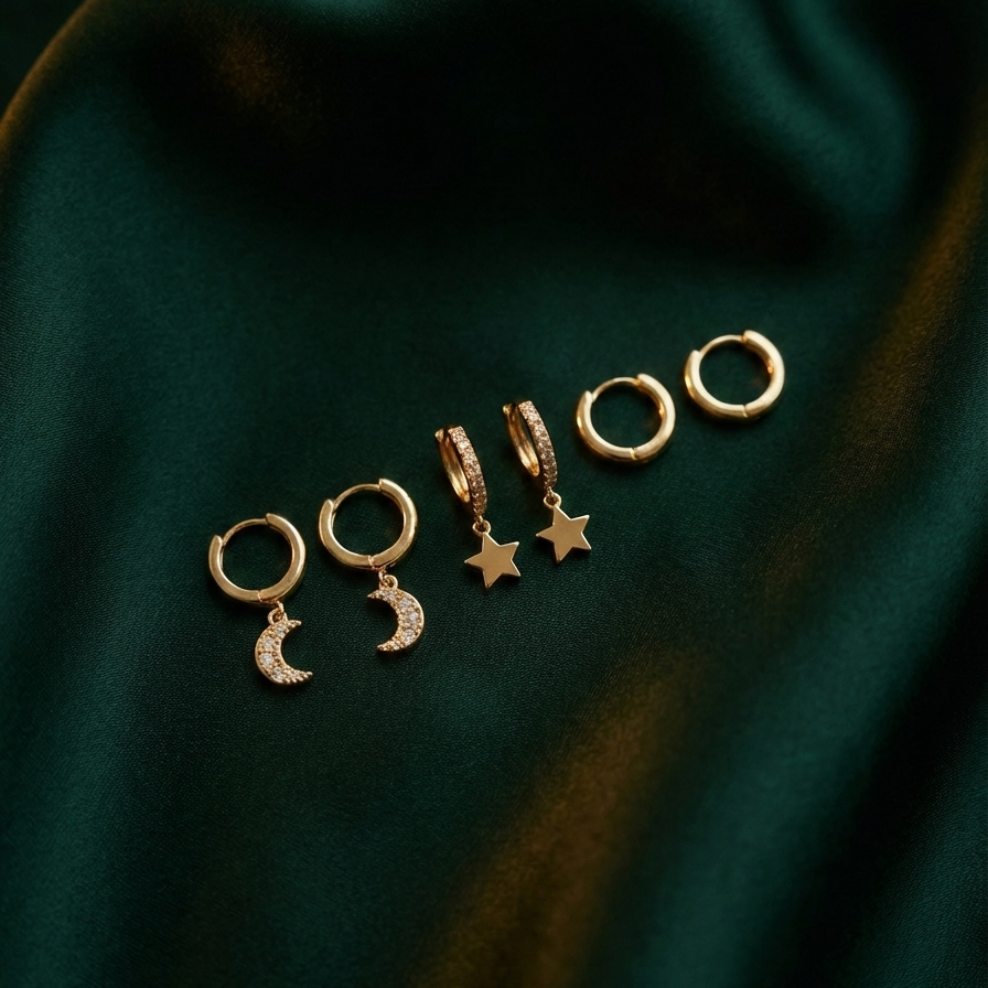 Set of gold huggie earrings with dangling star and moon charms on packaging card.