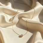 Single round crystal solitaire pendant necklace on white fabric background.