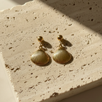 Gold shell drop earrings with scallop charm on white packaging card