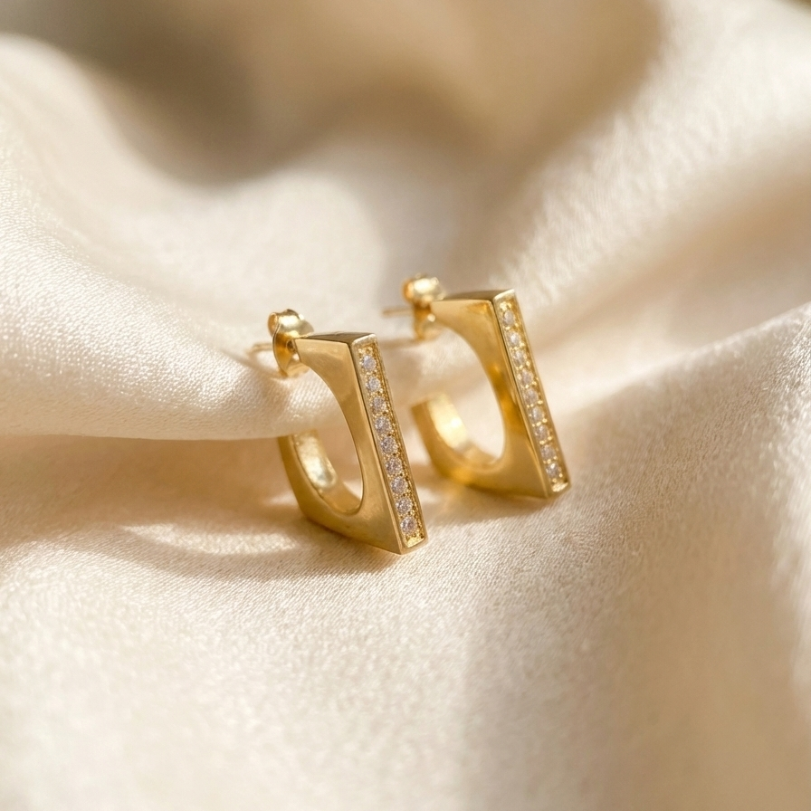 Rectangular gold hoop earrings with crystal pavé details on white background.