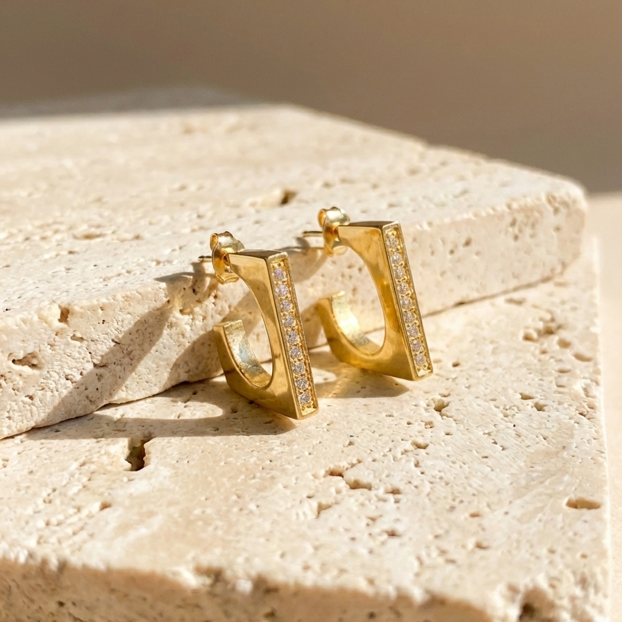 Rectangular gold hoop earrings with crystal pavé details on white background.