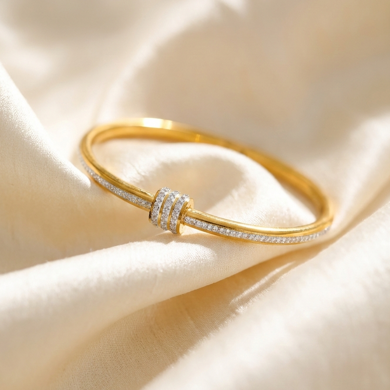 Gold bangle bracelet with triple row crystal center station on textured surface.