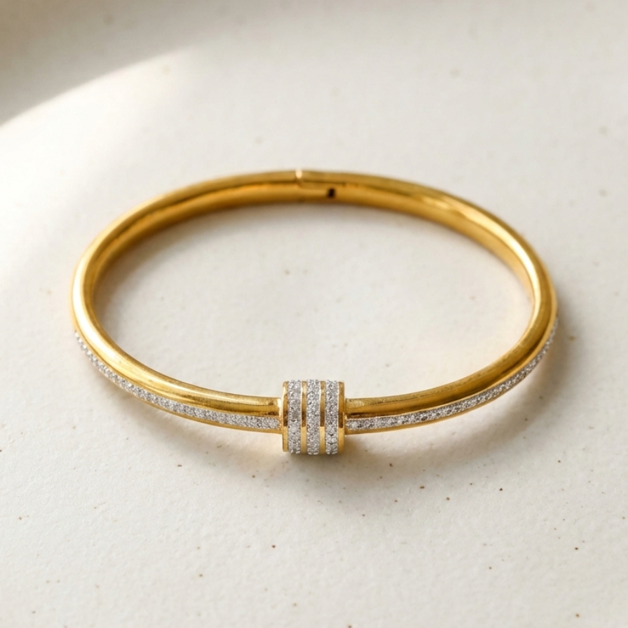 Gold bangle bracelet with triple row crystal center station on textured surface.