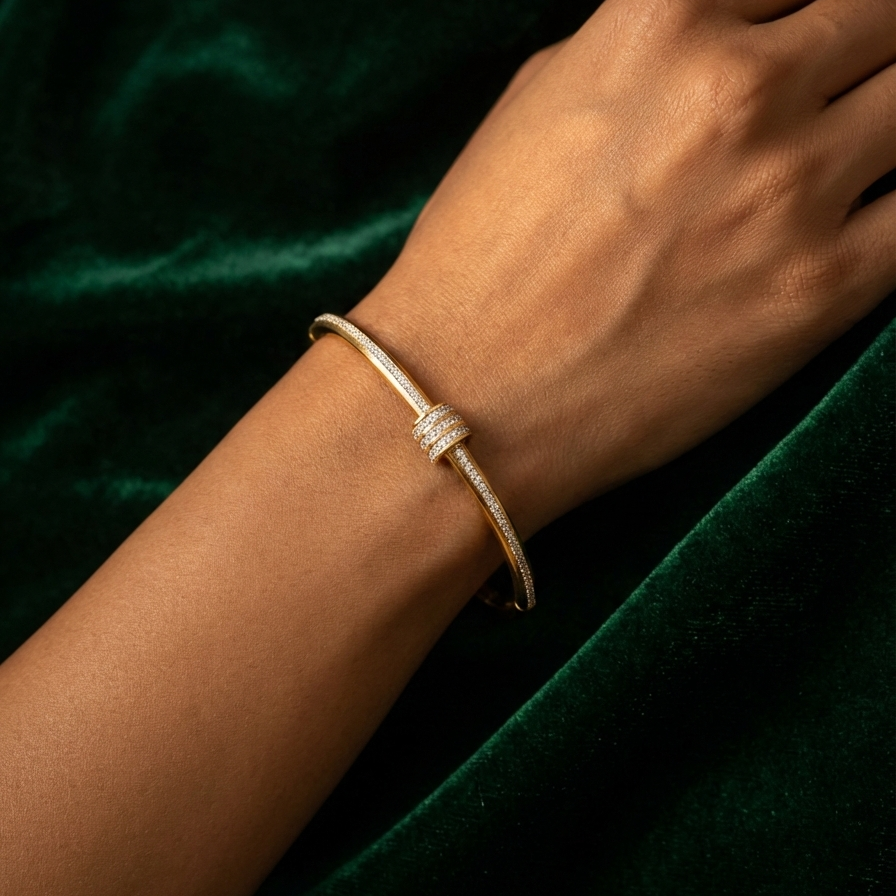 Gold bangle bracelet with triple row crystal center station on textured surface.