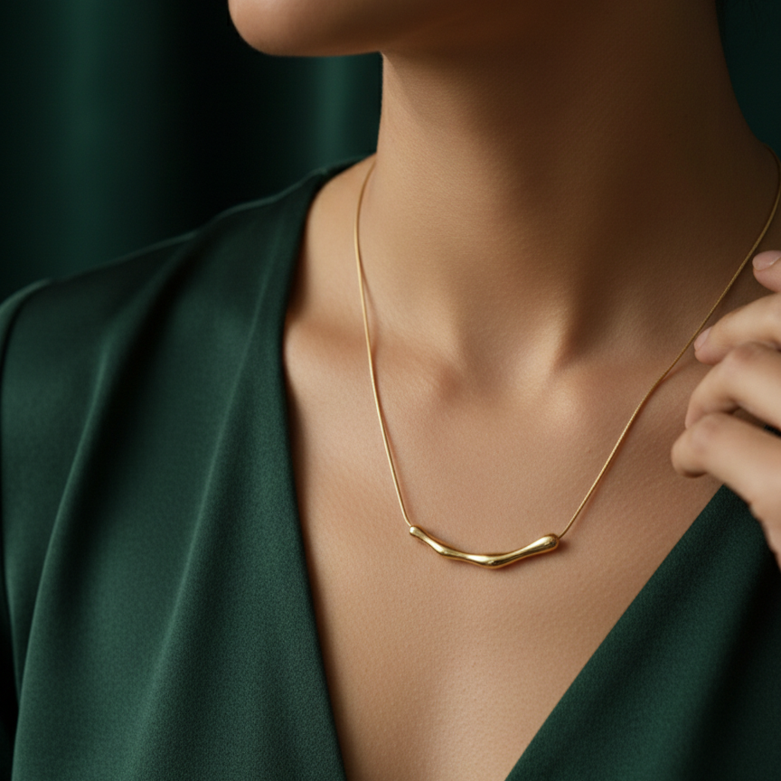 Gold necklace with curved bamboo texture bar sliding on a link chain on model neck.