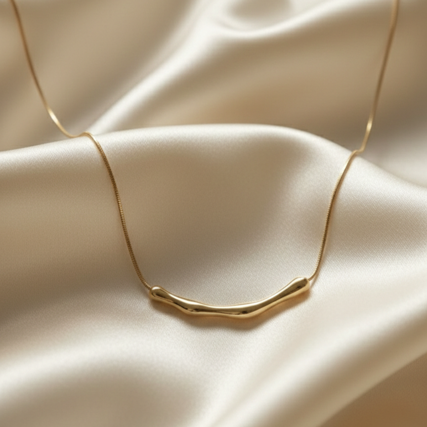 Gold necklace with curved bamboo texture bar sliding on a link chain on model neck.