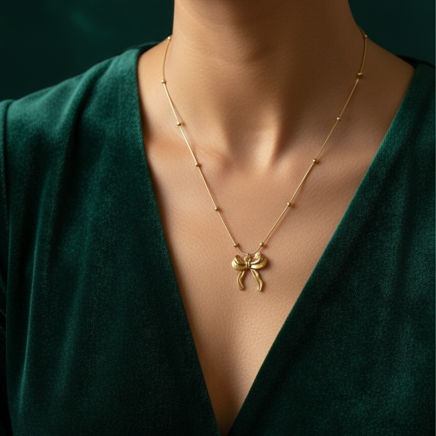 Gold 3D puffed bow necklace pendant on snake chain waterproof jewelry white background.