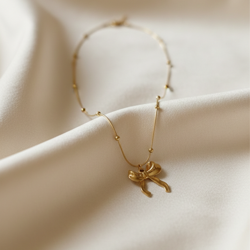 Gold 3D puffed bow necklace pendant on snake chain waterproof jewelry white background.