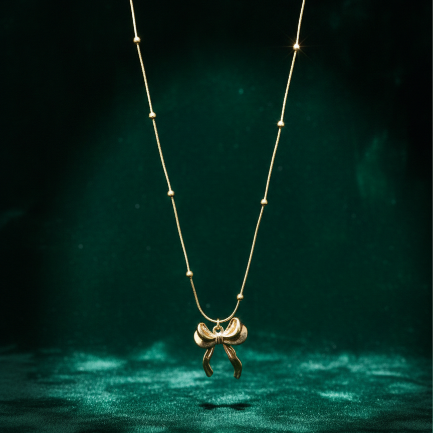 Gold 3D puffed bow necklace pendant on snake chain waterproof jewelry white background.