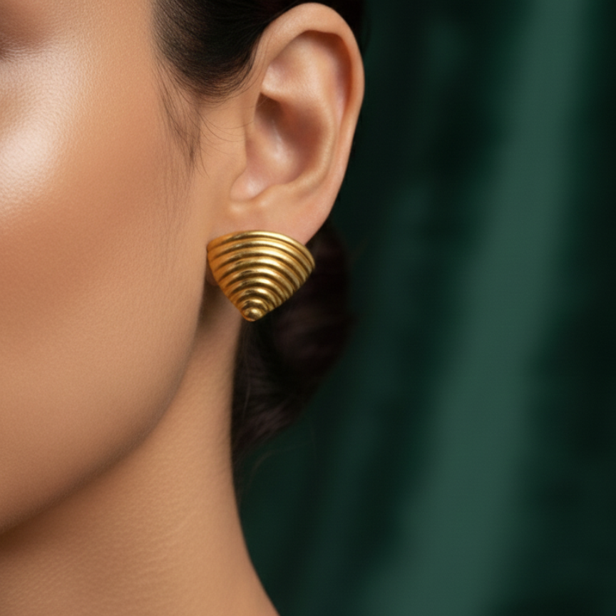 Ribbed gold croissant style triangular stud earrings on white background.