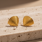 Ribbed gold croissant style triangular stud earrings on white background.