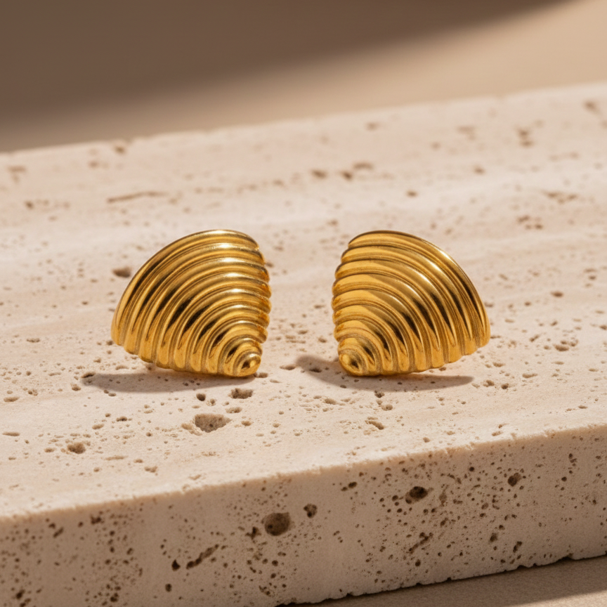 Ribbed gold croissant style triangular stud earrings on white background.