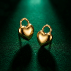 Gold puffy heart padlock earring worn on ear model.
