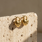 Gold puffy heart padlock earring worn on ear model.