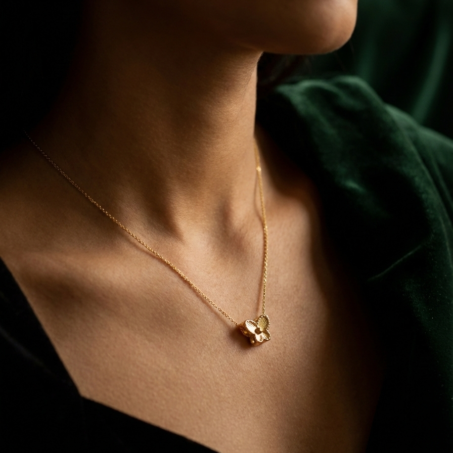 Small gold butterfly pendant with textured wings on white plate.