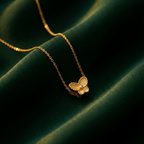 Small gold butterfly pendant with textured wings on white plate.