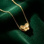 Small gold butterfly pendant with textured wings on white plate.