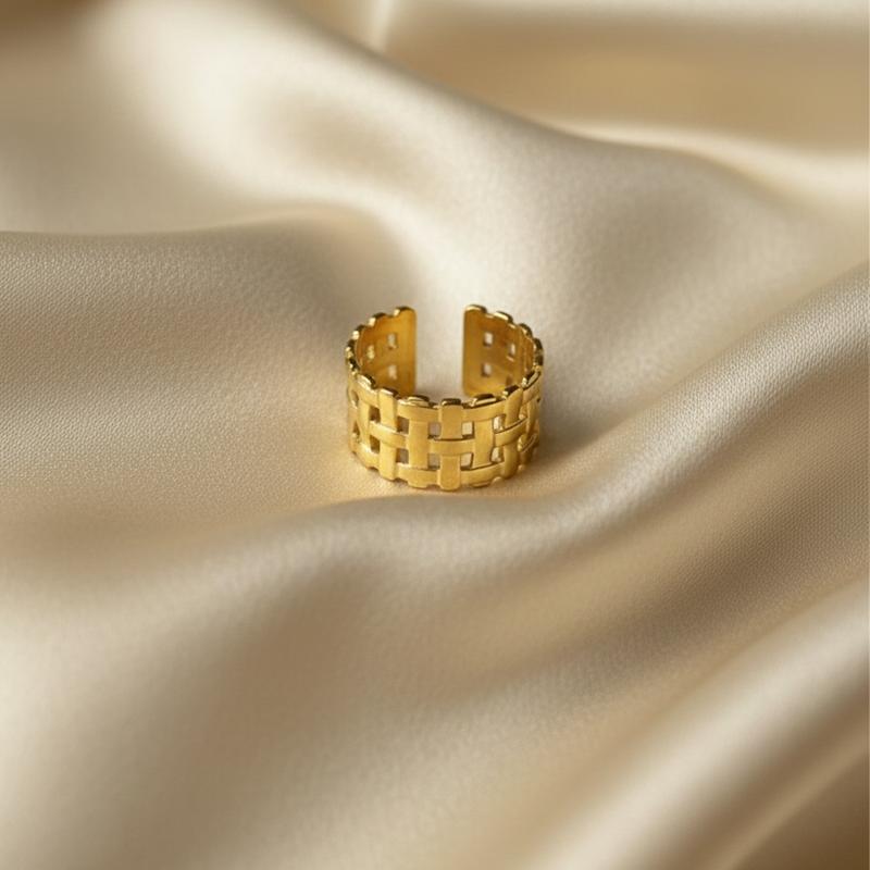 Wide gold ring with woven basket weave texture on white background.