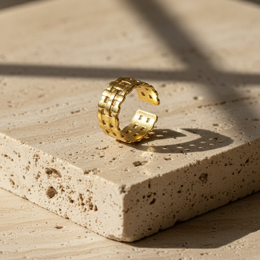 Wide gold ring with woven basket weave texture on white background.