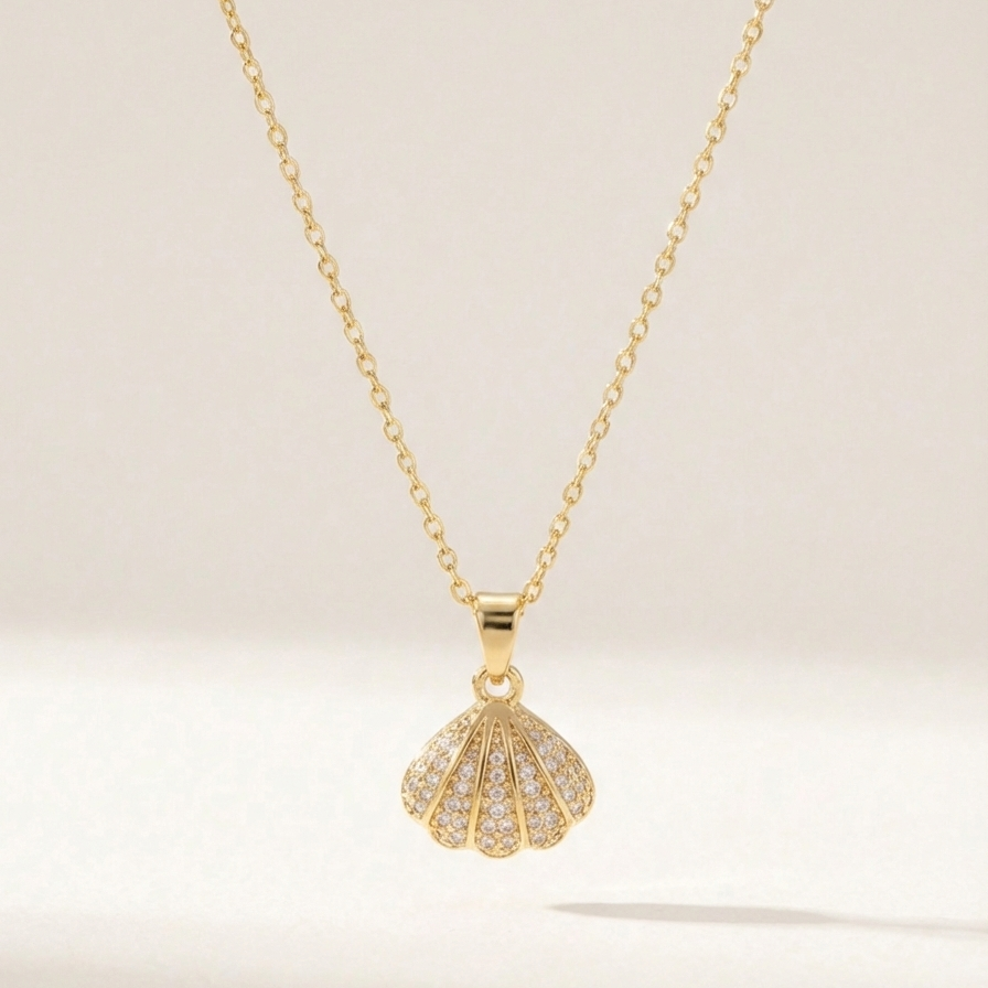 Gold shell locket necklace opened to reveal pearl inside on beige background.