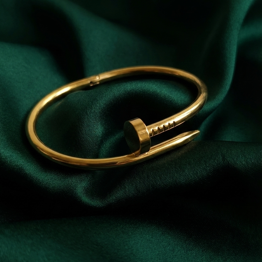 Gold bent nail design bangle bracelet on white stone prop.