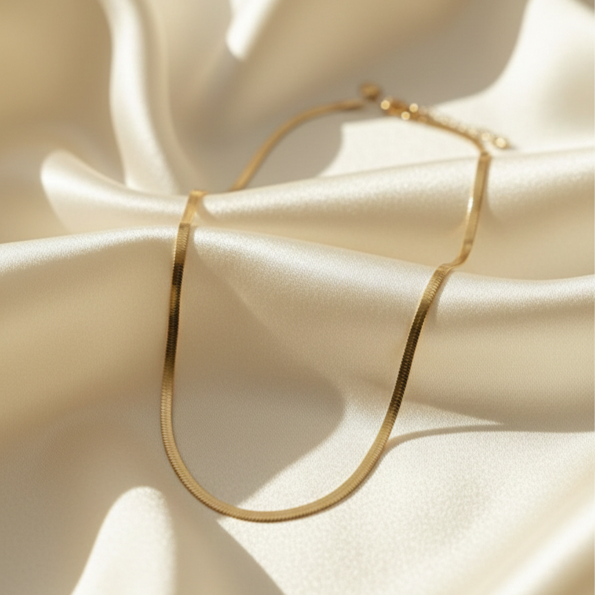Flat gold herringbone snake chain necklace liquid gold texture waterproof 18k plated on beige silk.
