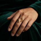 Gold wave ring with open adjustable design on white stone background.