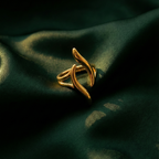 Gold wave ring with open adjustable design on white stone background.