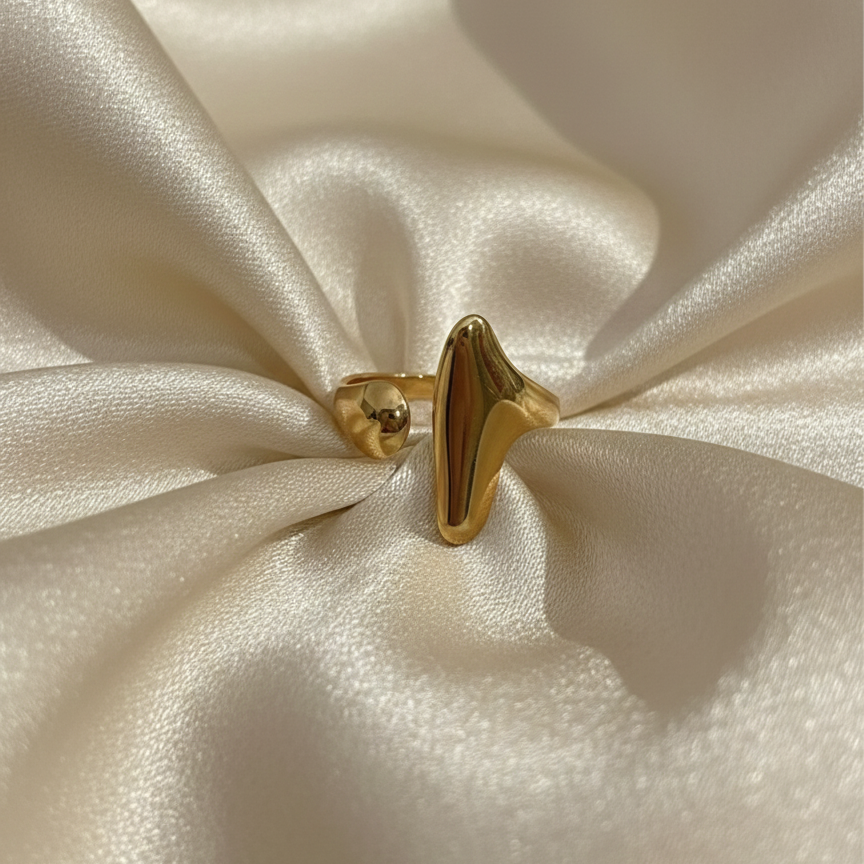 Abstract gold statement ring with elongated molten shape on white background.