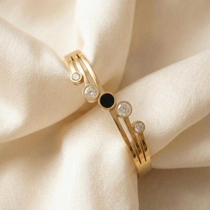 Gold hinged bangle bracelet with black stone and crystal circles on white stand.