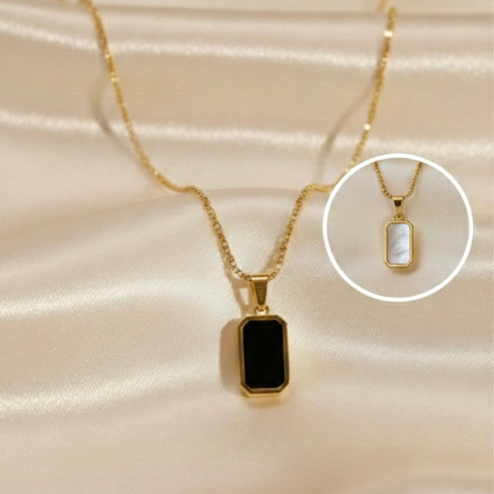 Reversible rectangular gold pendant necklace showing black side on model neck.