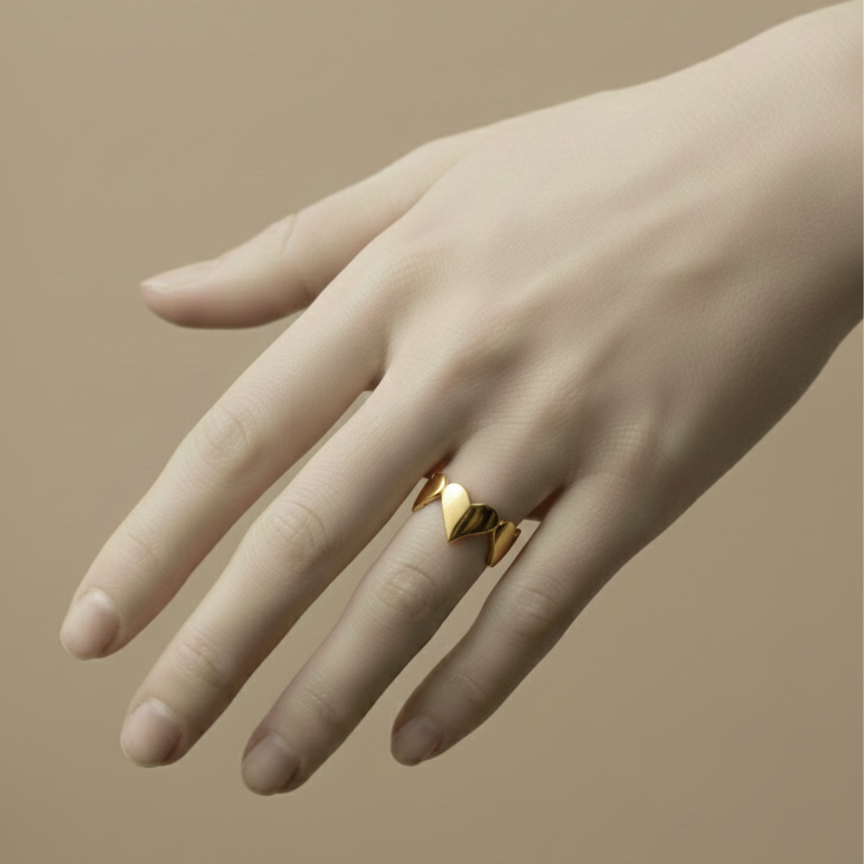 Gold heart shaped ring with crown details on beige background.