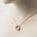 Gold necklace with a heart-shaped pendant on a mannequin.