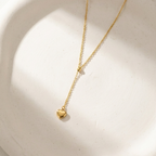 Model wearing gold Y-shape lariat necklace with heart drop on black shirt.